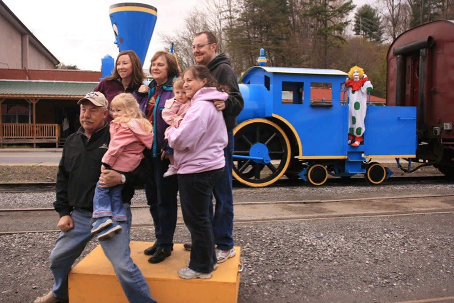 A family of seven poses for a picture in front of a blue steam engine