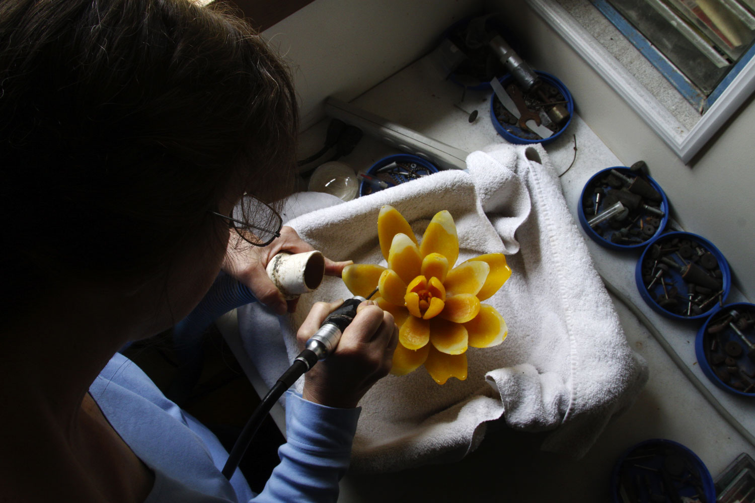 A woman works on a glass flower sculpture