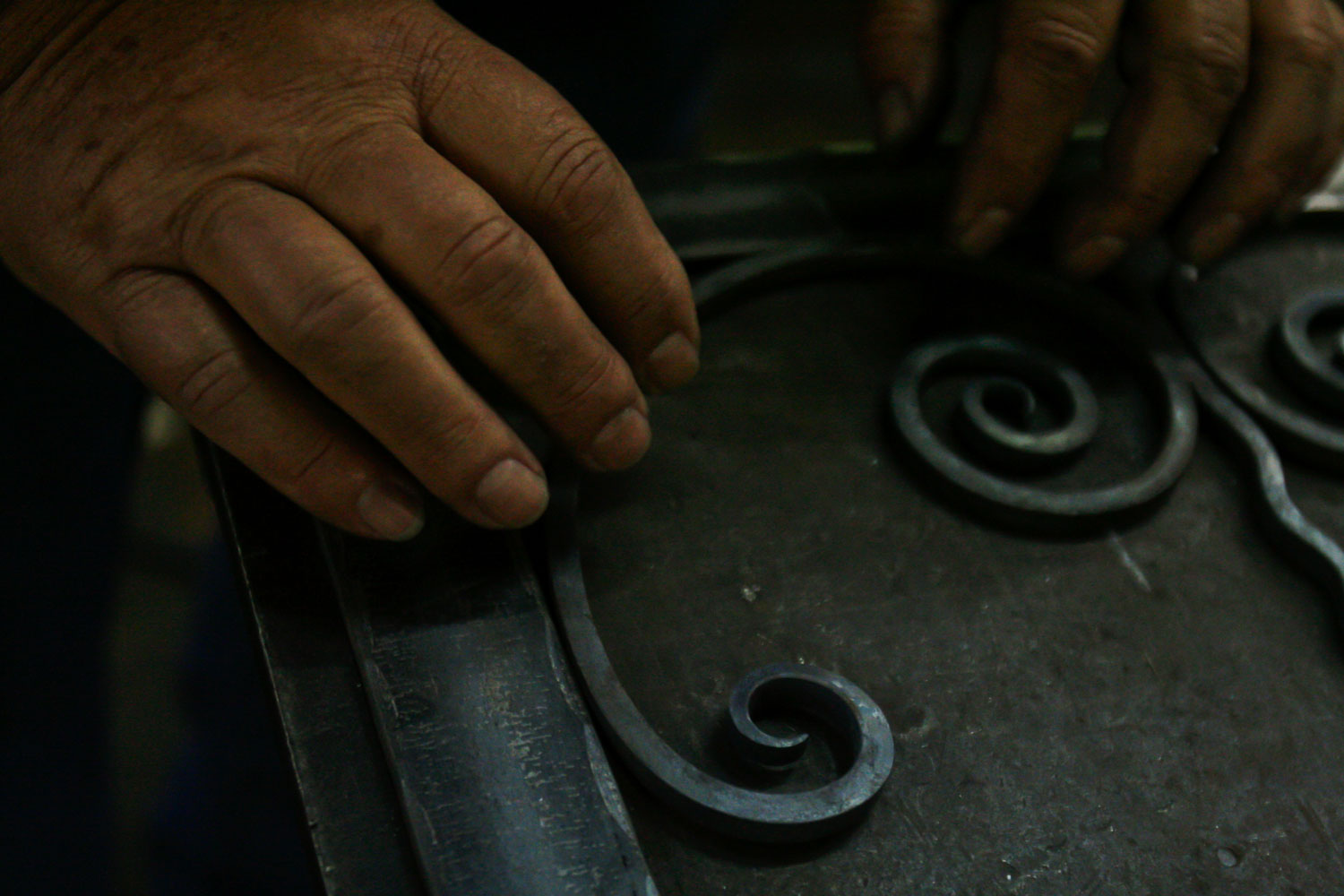 A pair of hands work on iron decor
