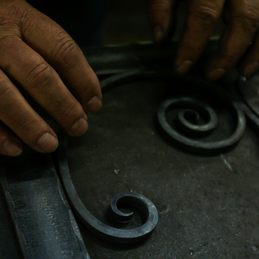 A pair of hands work on iron decor