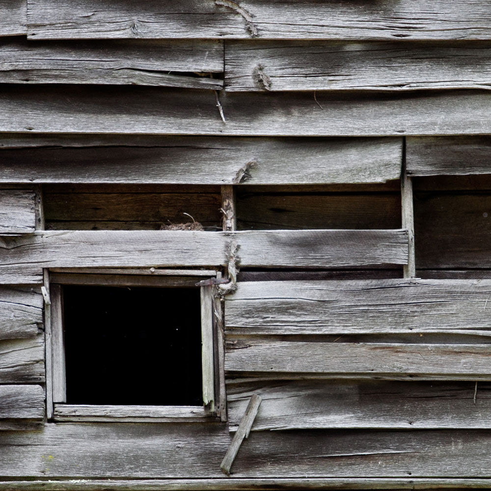 A pair of windows on an old, wooden grain mill