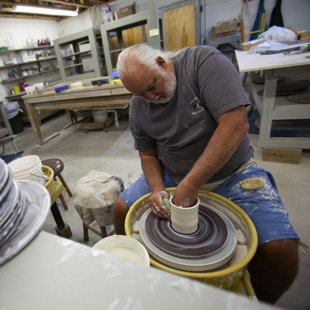 A man works on a ceramic on a pottery wheel