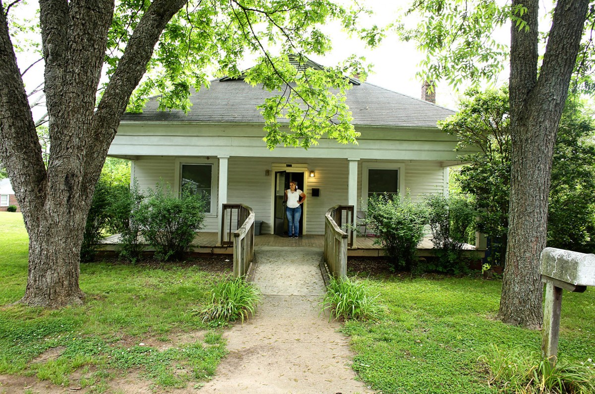 Catie Brown standing on the porch of her home on a warm summer day.