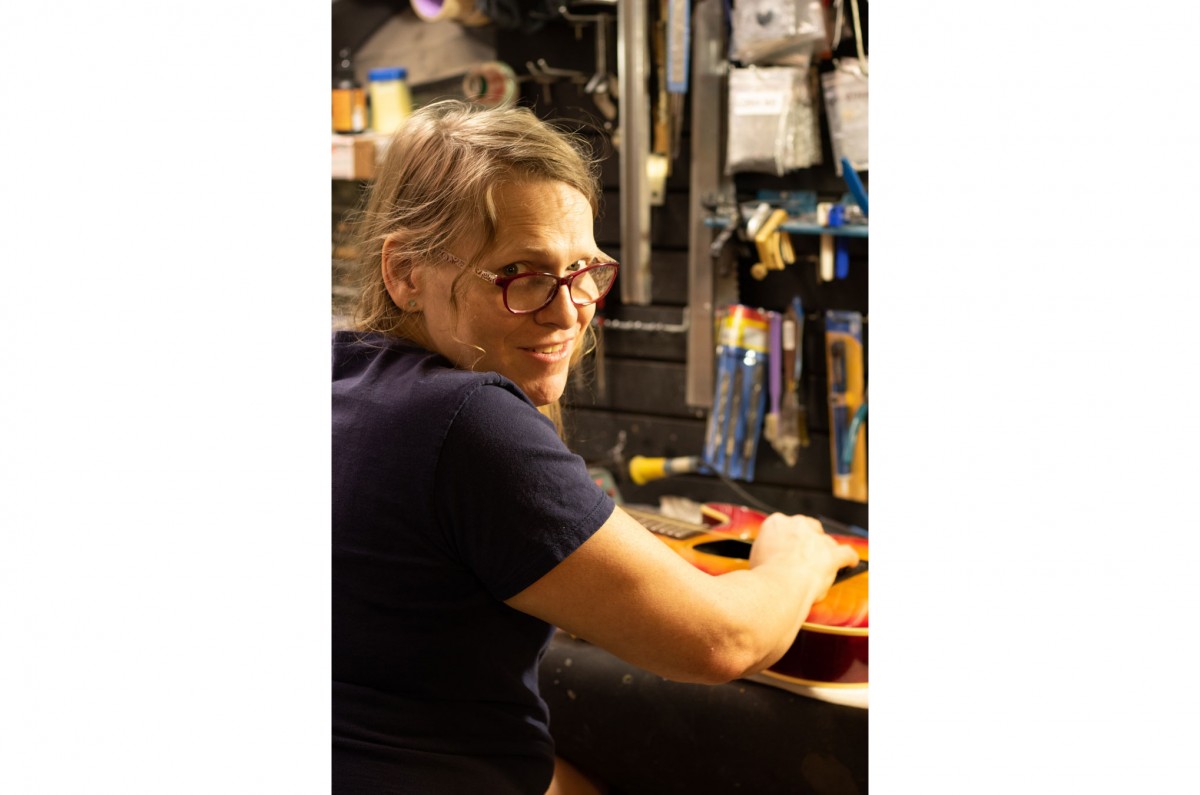 Samantha Marshall, a self-taught luthier (someone who repairs guitars), poses in front of her work station in the basement of Larry’s Music and Sound Store.