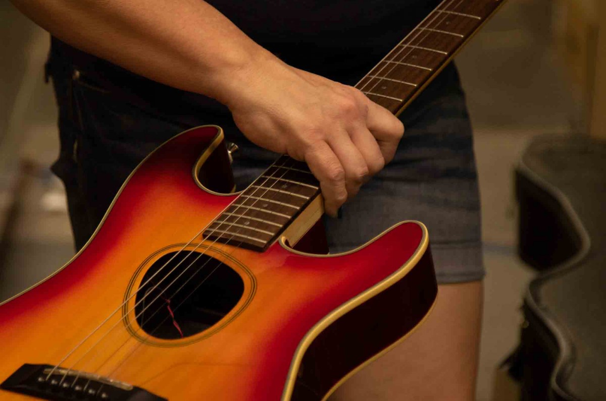 Samantha carries a customer’s guitar back to her work station.