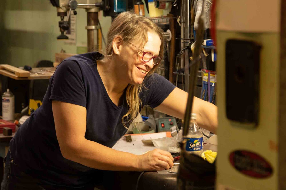 After finishing the pickup replacements on a customers guitar, Samantha laughs at a joke made by her coworker Scott while she cleans up her work station.