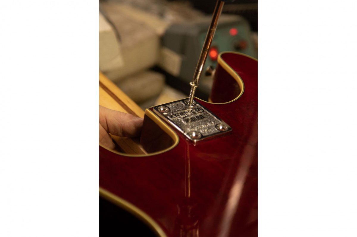 Samantha screws the neck of the guitar off so that she can reach the pickups inside the guitar through the hole of the body.