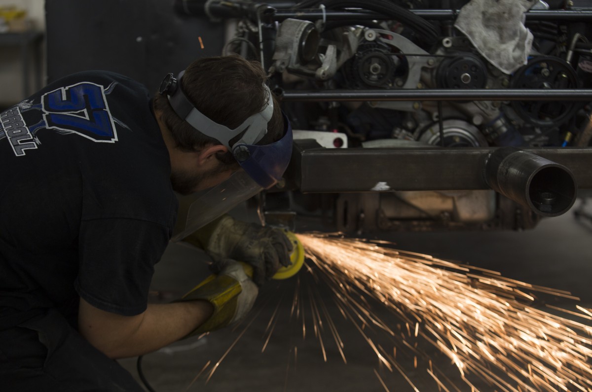 Justin Carroll cuts and sands metal in order to be able to add a new part onto his car druing work at Performacenter Racing Warehouse.
