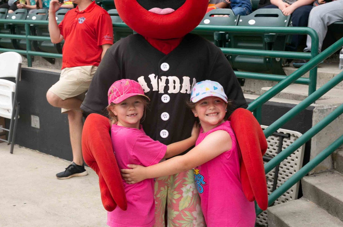 Two fans hug Conrad the Crawdad at the baseball game on the L. P. Frans Stadium on May 15th, 2018.