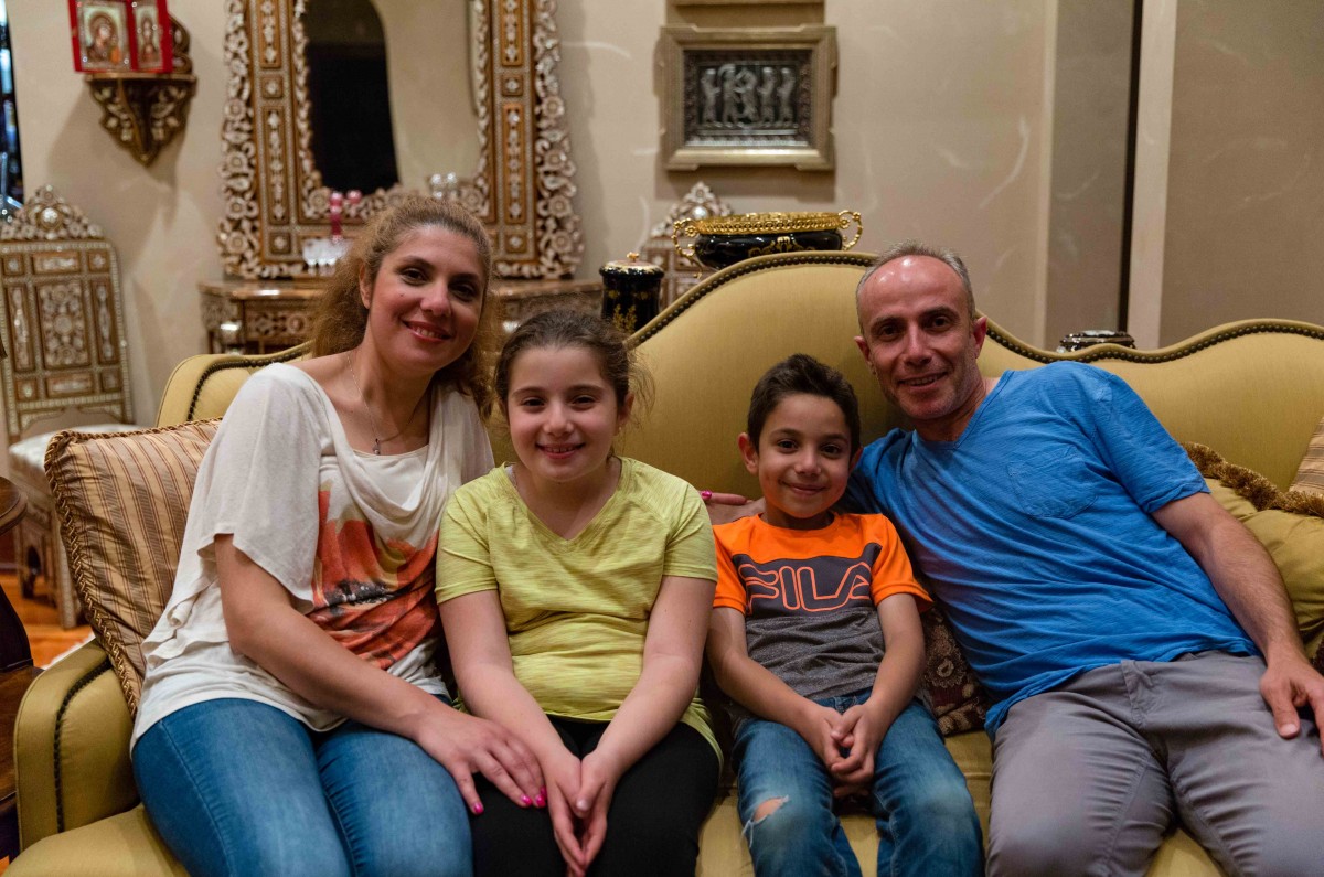 Mayada, Julia, Zain, and Raed pose together as a family during a gathering in the Alkoutami home. “They love the life here,” said Raed. “At least they feel safe.”