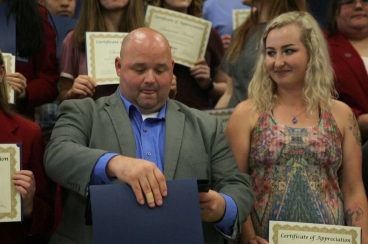 Ledford looks at an award he received for SkillsUSA at Catawba Valley Community College before posing for a group photo with all of the award recipients.