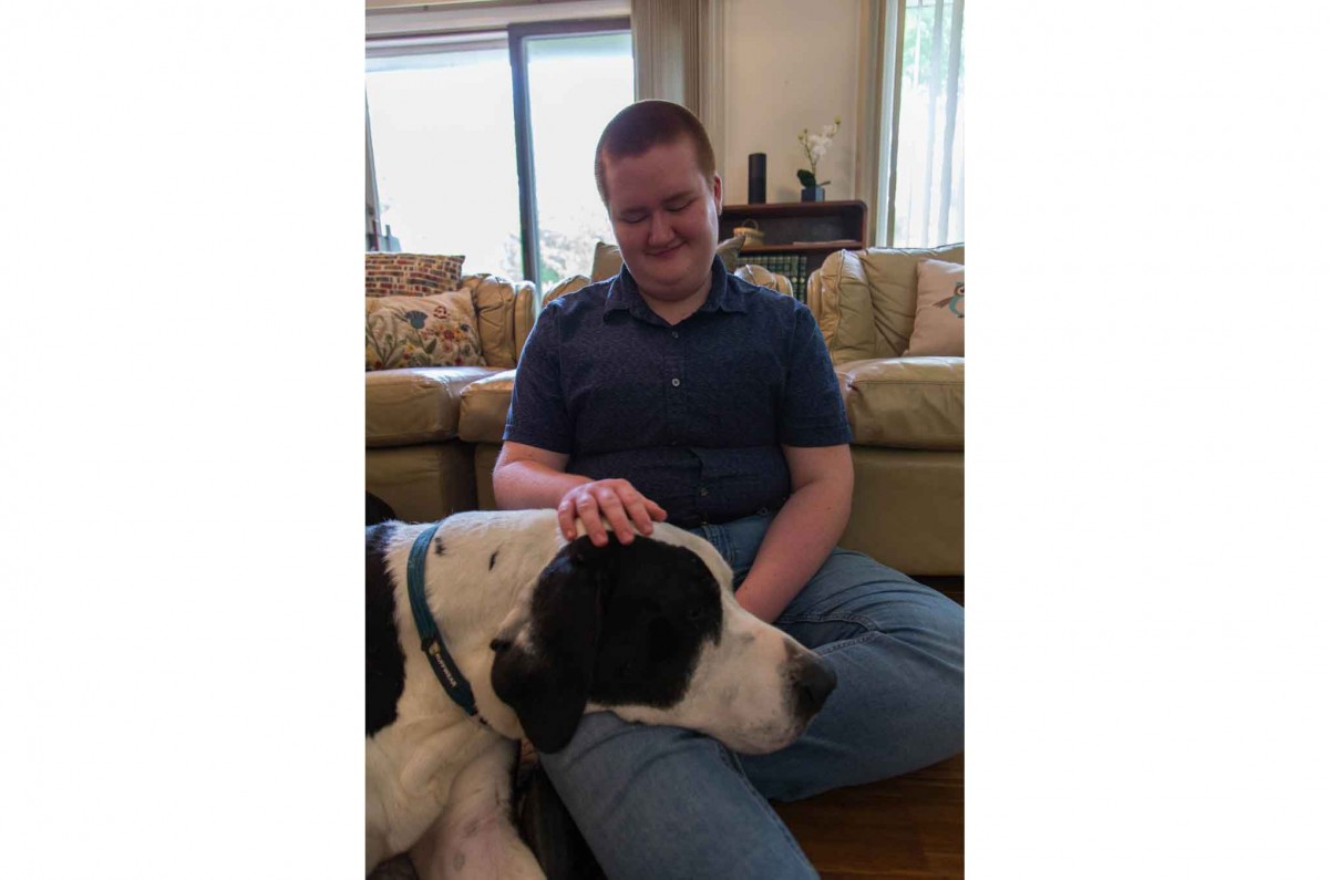 Theo rests in his living room with his dog, Norbert, a 160lb Great Dane.