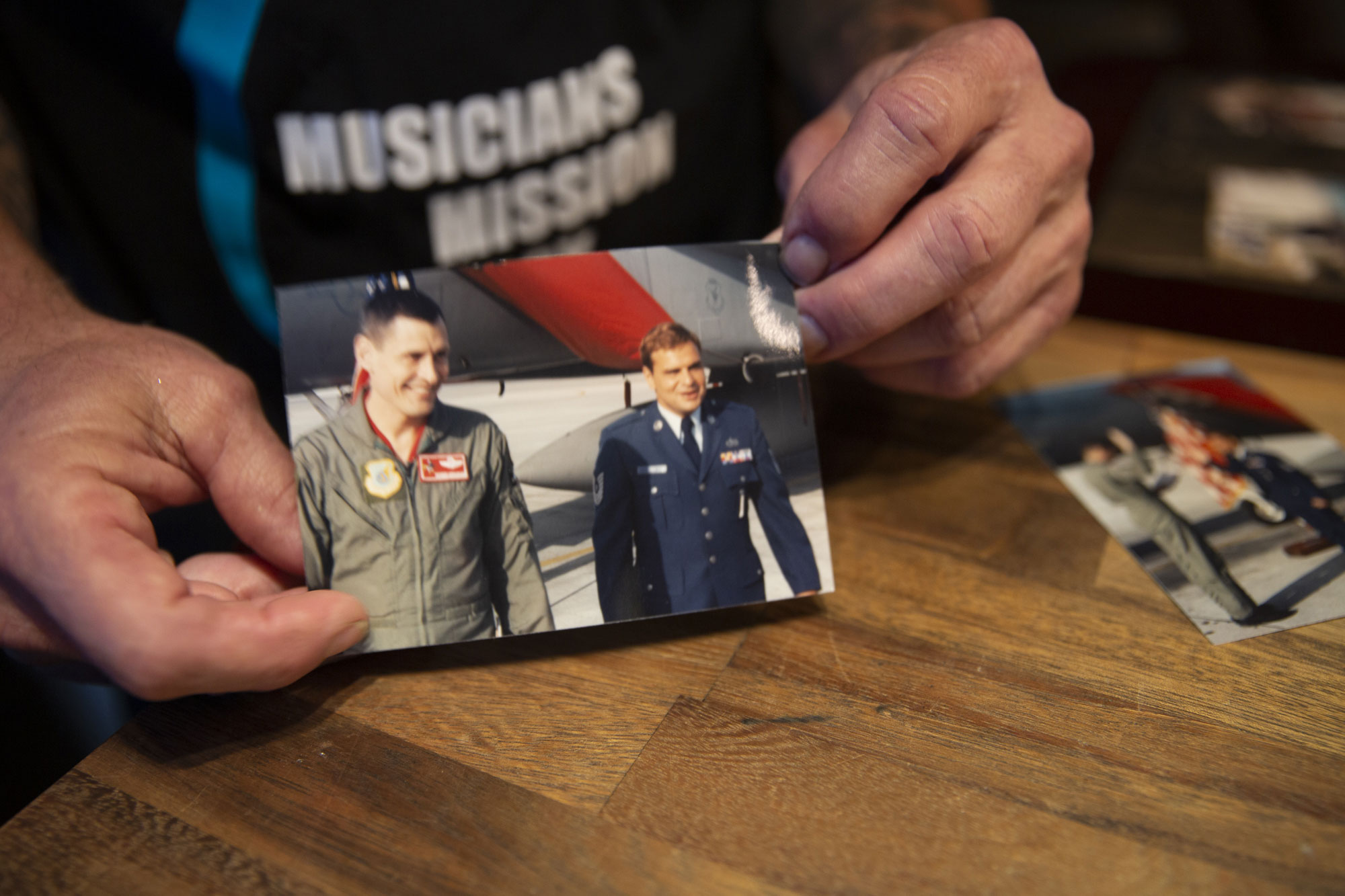 Man holds up a picture of him in his military uniform