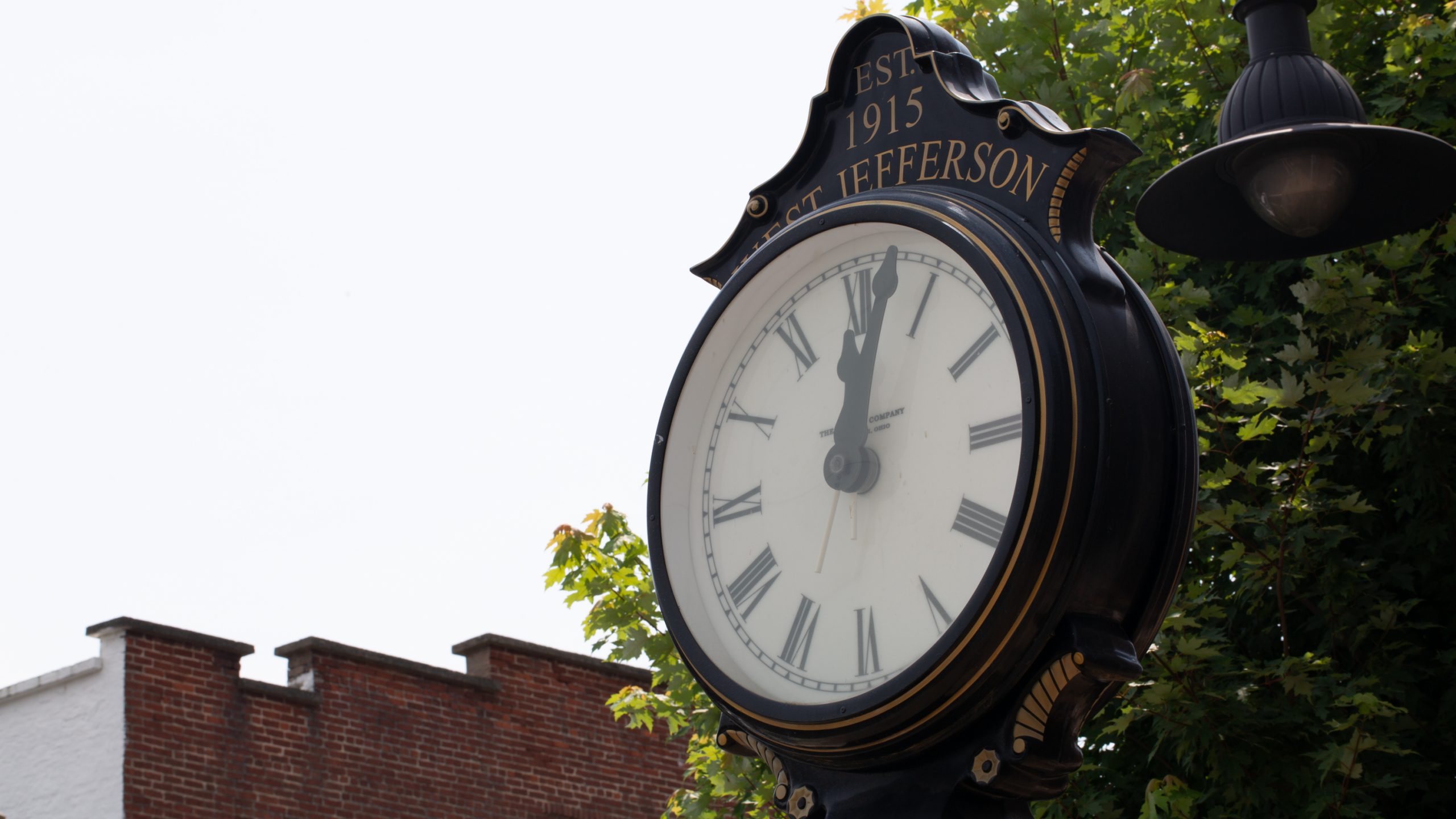 A clock points to 12:03 in a town square