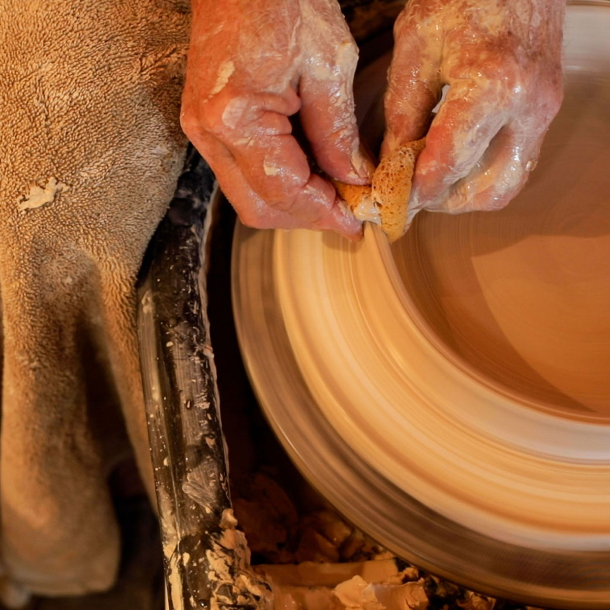 Hands on a piece of pottery on a wheel