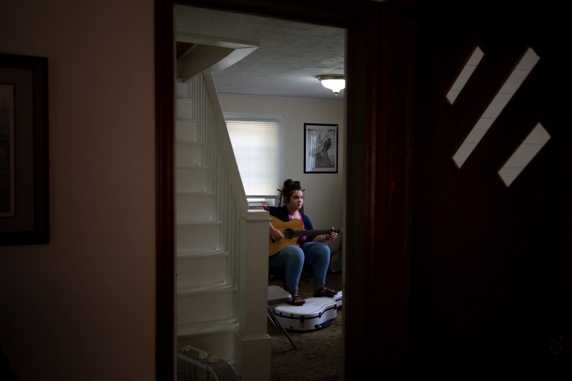 Shot through a door of a girl playing the guitar
