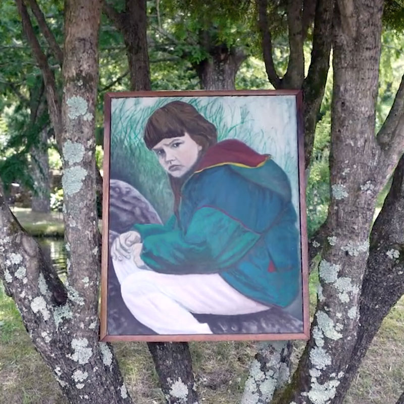 A painting of a girl hunched over in a green jacket sits in the branches of a tree