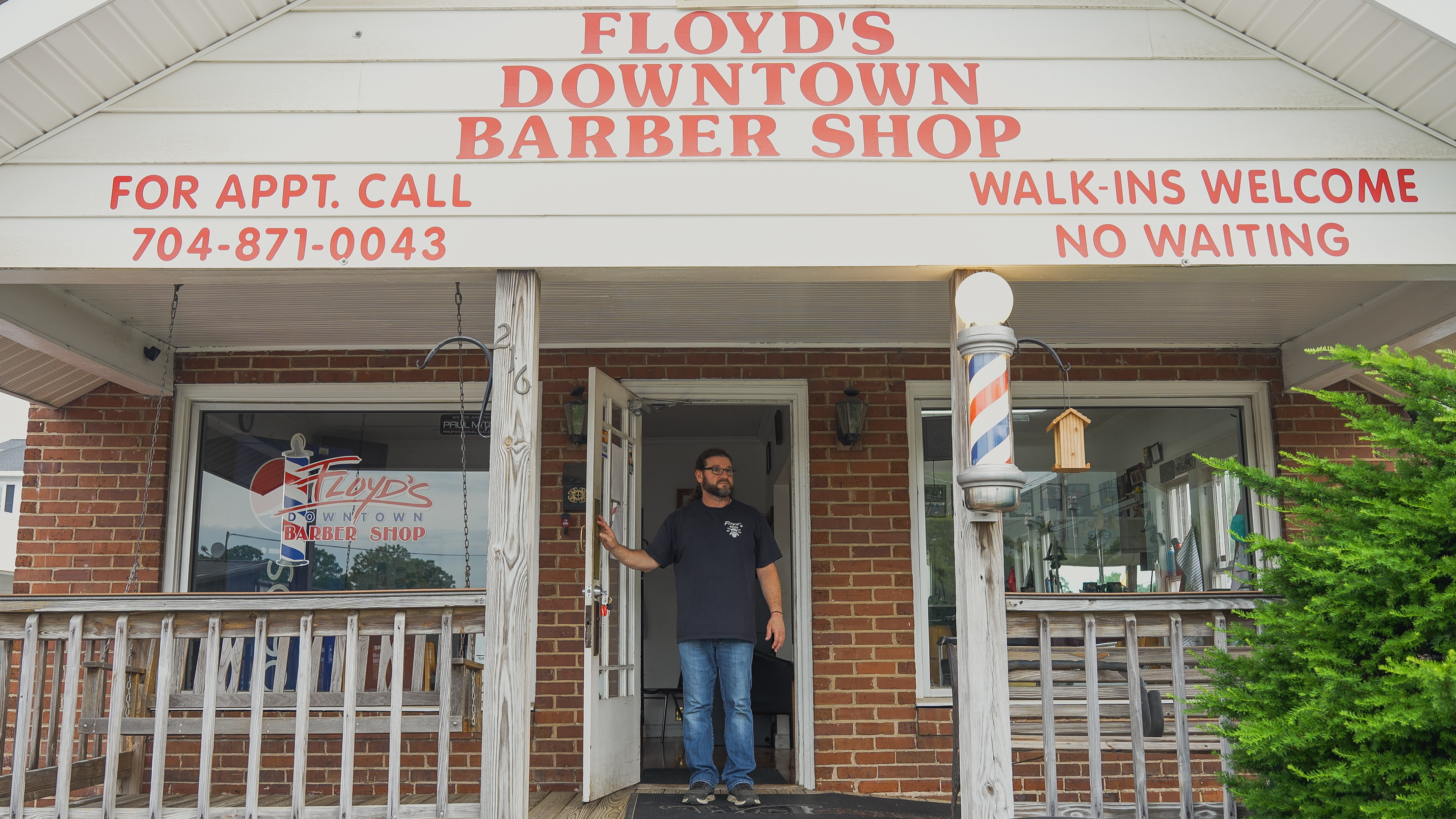 man in front of his barber shop
