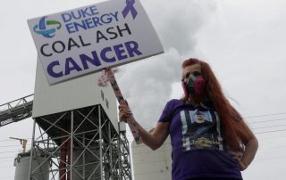 woman holding a sign that says "coal ash cancer"