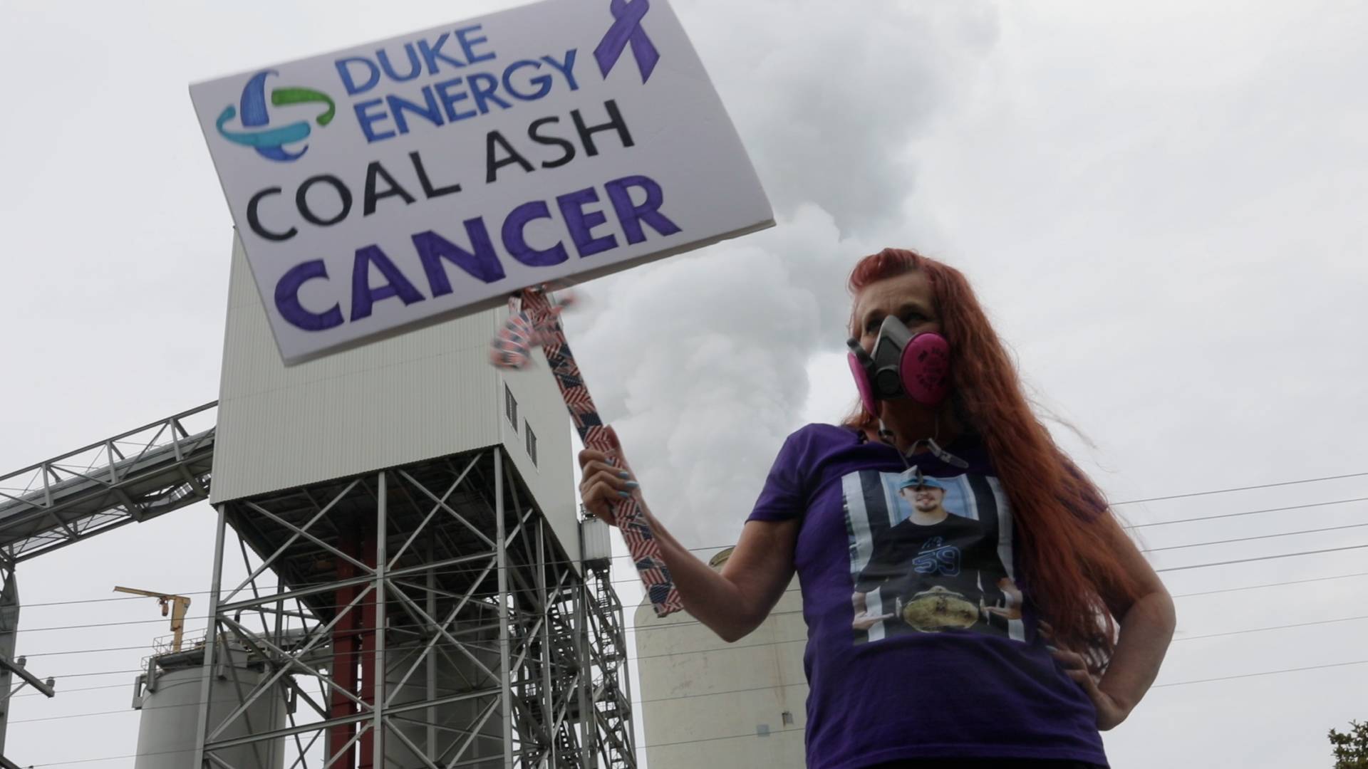 woman holding a sign that says "coal ash cancer"