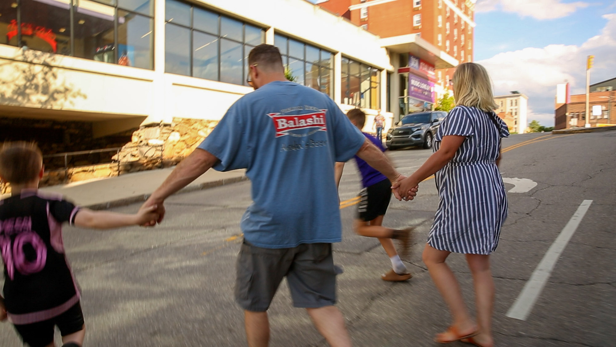 Kristen and her Husband Evan cross the street with their two kids towards the Civic Center in downtown Asheville, this is where the one year Hurricane Helene reunion will be held in September.
