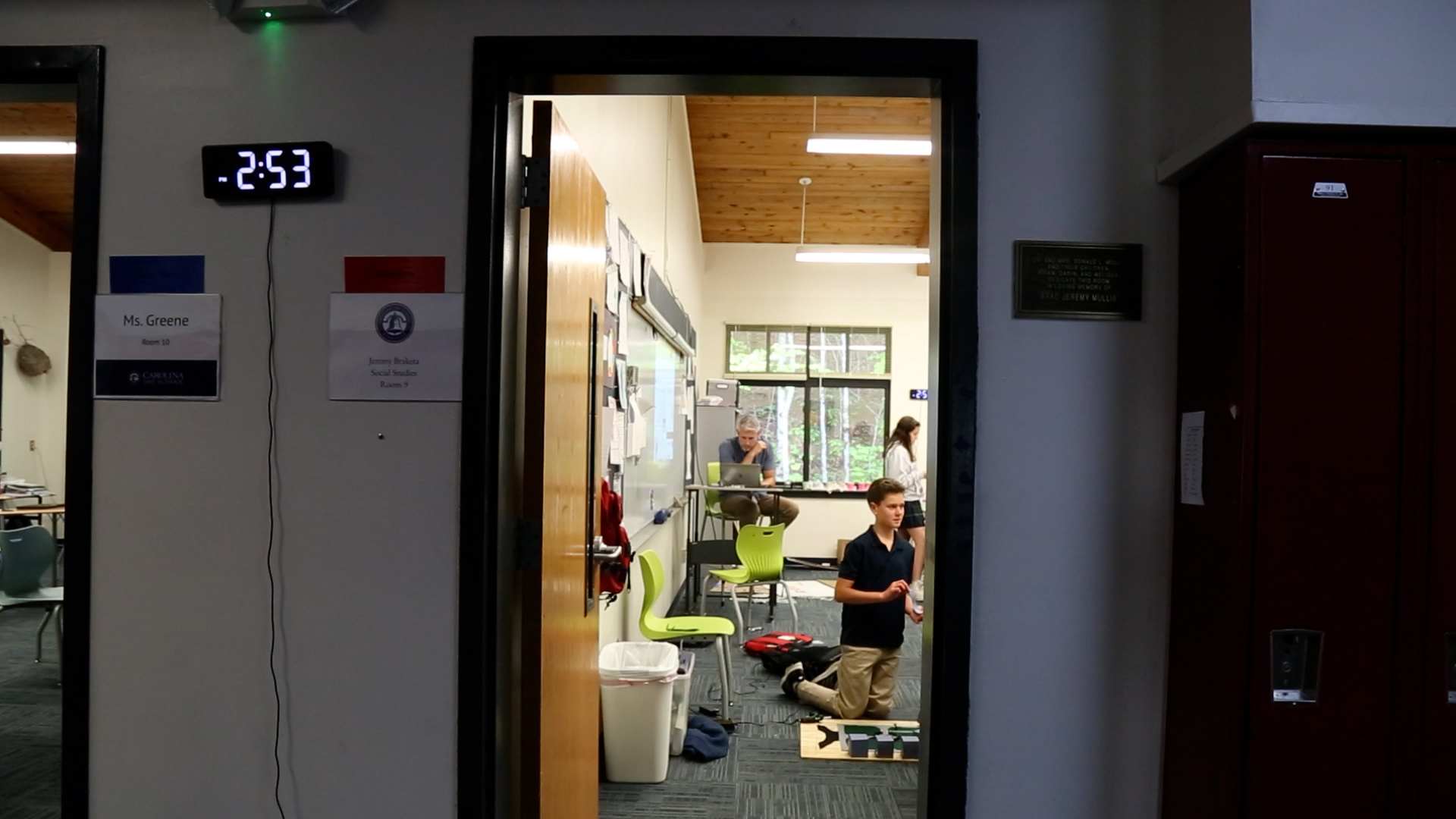 Jeremy Braketa sits at his desk in a rare moment of peace as students run around the class chaotically adding the finishing touches to their projects.