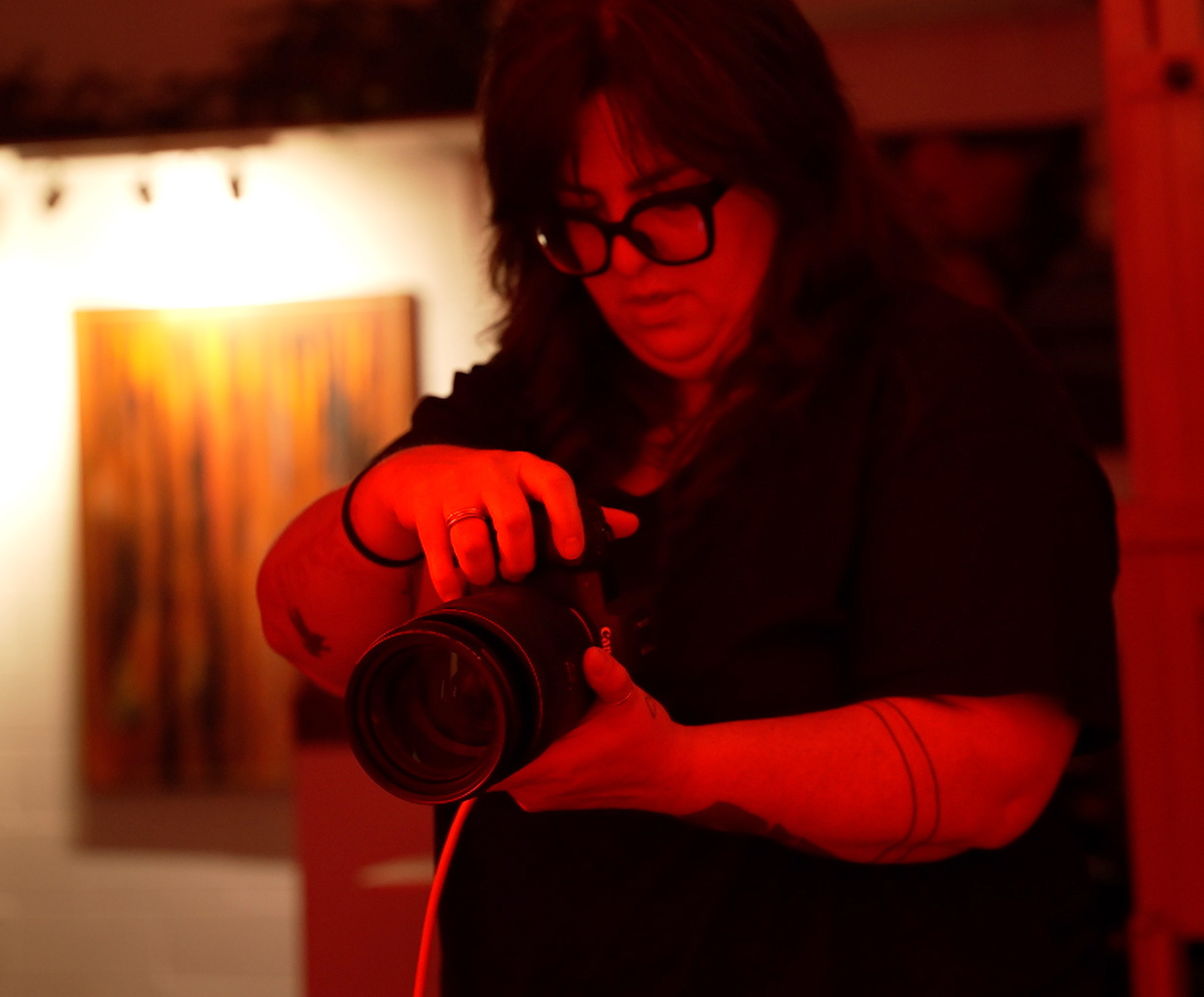 Fumberg directs her model as she snaps portraits of her under a red key light.